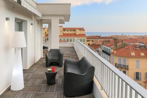 a balcony with two chairs and a view of a city at Ibis Styles Menton Centre in Menton