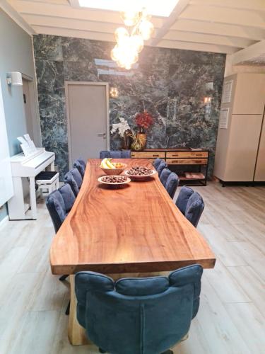 a dining room with a wooden table and blue chairs at Lazy Olives in Tongeren
