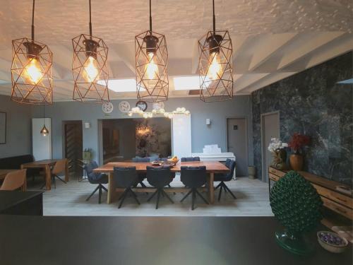 a dining room with a table and chairs and lights at Lazy Olives in Tongeren