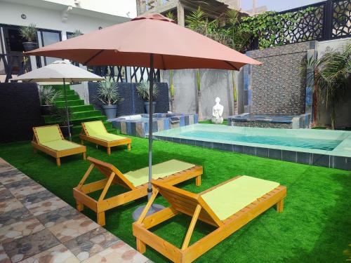 um par de cadeiras e um guarda-sol ao lado de uma piscina em La residence latinaya em Poponguine