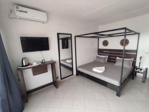 a bedroom with a canopy bed and a television at La residence latinaya in Poponguine
