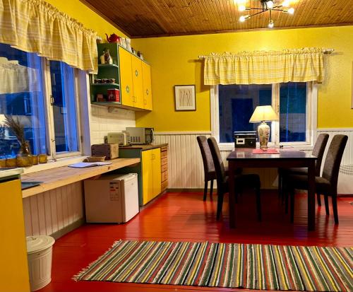 d'une cuisine avec une table, des chaises et des murs jaunes. dans l'établissement Suojelumetsän sylissä oleva talo lähellä vesistöjä, à Keuruu