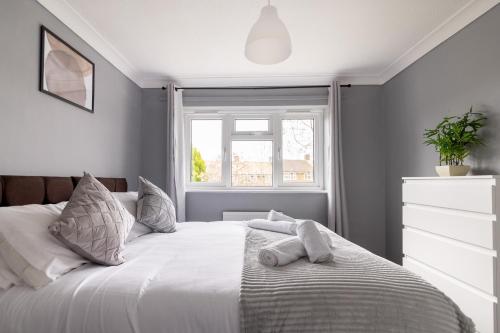 um quarto com uma cama branca e toalhas em The Kilnwood House em Crawley