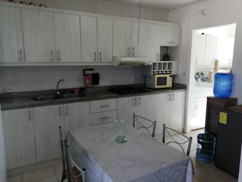 uma cozinha com armários brancos e uma mesa com uma janela em Arenys IV em Tonsupa