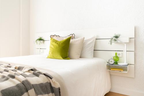 - une chambre avec un lit blanc et un oreiller jaune dans l'établissement Increíble, amplio, cómodo y céntrico apartamento, à Pampelune