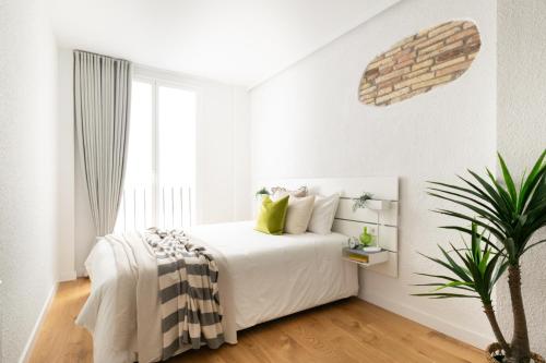 - une chambre blanche avec un lit et une plante en pot dans l'établissement Increíble, amplio, cómodo y céntrico apartamento, à Pampelune