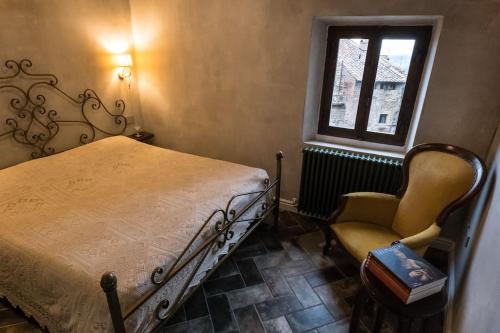 um quarto com uma cama, uma cadeira e uma janela em The Balcony in Tuscany em Anghiari