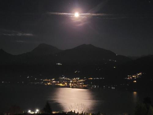 a full moon rising over the water at night at PARADISE VILLA VISTA LAGO DI COMO A MENAGGIO in Menaggio