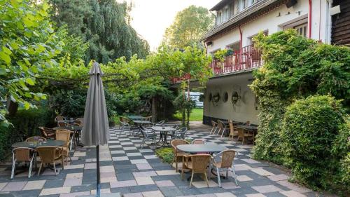an outdoor patio with tables and chairs and an umbrella at Das Wiesenhaus Wohnen im Schlaffass in Cologne