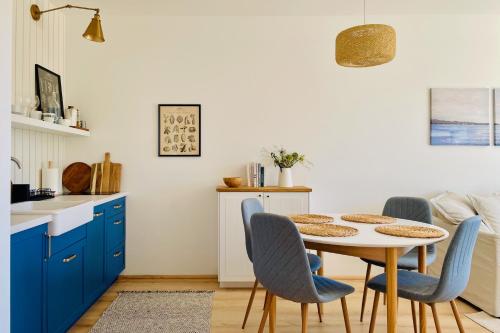 a kitchen with blue cabinets and a table and chairs at 500m Sea, Terrace - Sunny Calm Coastal Retreat in Dźwirzyno