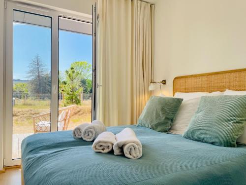 1 dormitorio con toallas en una cama con ventana en 500m Sea, Terrace - Sunny Calm Coastal Retreat en Dźwirzyno