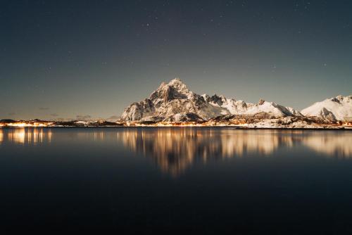 a mountain reflecting in the water at night at Skårungen - Hotel, Cabins and Camping in Kabelvåg