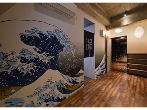 a room with a painting of a wave on the wall at Santiago Guesthouse Naha - Vacation STAY 86305v in Naha