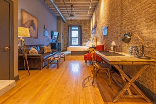 a living room with a table and a brick wall at Hip Urban Loft-Small Town Charm-124 LOFTS #2 in West Dundee
