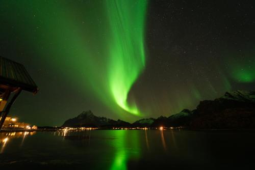 an aurora in the sky over a body of water at Skårungen - Hotel, Cabins and Camping in Kabelvåg