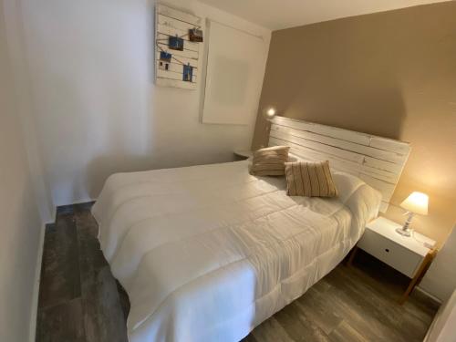 ein Schlafzimmer mit einem weißen Bett und einem Nachttisch mit einer Lampe in der Unterkunft Apartamento Pleamar in El Rompido