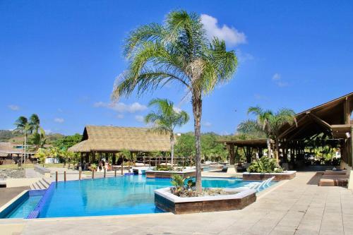 einen Pool mit einer Palme neben einem Gebäude in der Unterkunft Next To Beach Club Blue 2 Bedroom Family Villa in Playa Venao