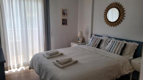 Un dormitorio blanco con una cama grande con toallas. en La Casa de los Peces, en Peñíscola