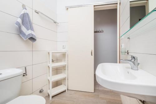 a white bathroom with a sink and a toilet at City Life Marina apartment No. 5 in Ampavris
