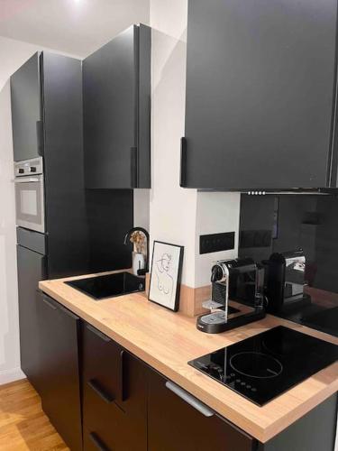 La cuisine est équipée d'un évier et d'un réfrigérateur noir. dans l'établissement Appartement d'architecte, Paris-République 2P, à Paris