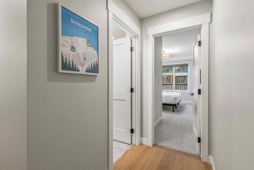 a hallway with a door leading into a room with a painting at Brand New - TimberLodge Spacious 2br in Canmore