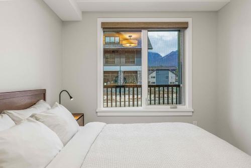 a white bedroom with a bed and a window at Brand New - TimberLodge Spacious 2br in Canmore