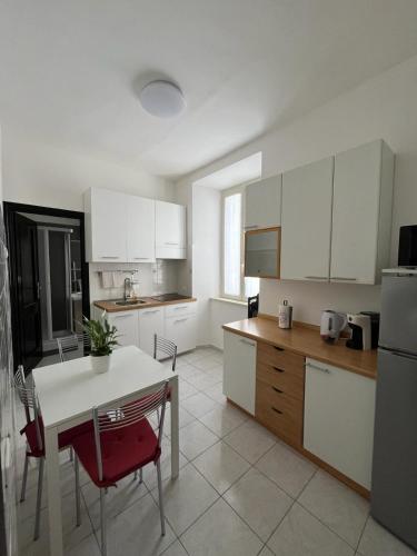 uma cozinha com armários brancos e uma mesa e cadeiras em Luna Apartment em Civitavecchia
