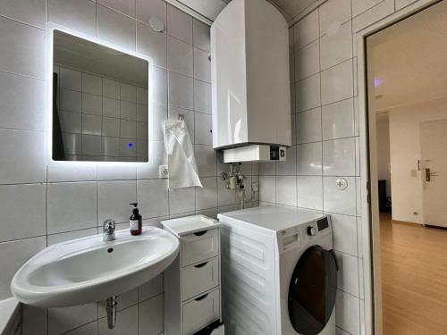La salle de bains blanche est pourvue d'un lavabo et d'un lave-linge. dans l'établissement Über den Dächern Grillen in bester Lage Innenstadt/Stellplatz, à Heilbronn