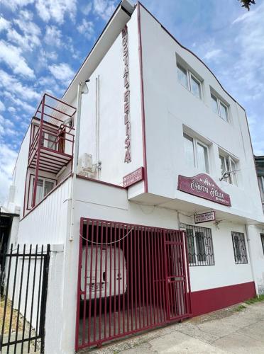 un bâtiment blanc avec une porte rouge devant lui dans l'établissement Hostal Feliza, à Valdivia