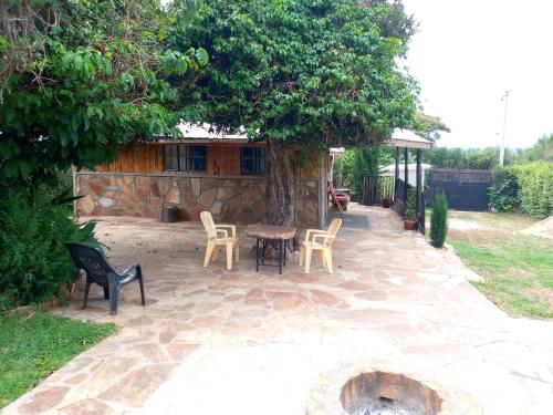 a patio with a table and chairs under a tree at Esam Homestay in Sekenani