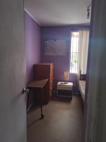 1 dormitorio con paredes de color púrpura, 1 cama y escritorio en Pieza individual con baño privado en sector Puertas del mar en La Serena