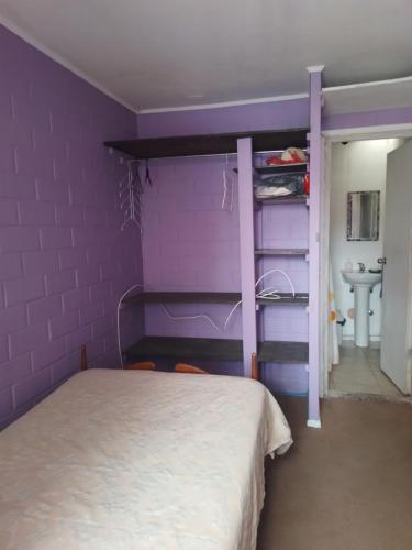 Dormitorio púrpura con cama y lavabo en Pieza individual con baño privado en sector Puertas del mar, en La Serena