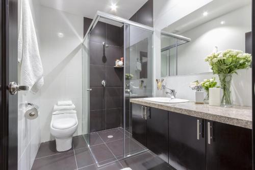 a bathroom with a toilet and a glass shower at Gaviota Apartments & Suites in Cuenca