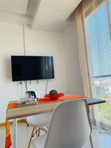 a room with a table with chairs and a flat screen tv at SuAparts in Praia