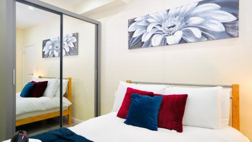 1 dormitorio con cama y espejo en F3 Ground floor Luxury flat Gants Hill, en Redbridge