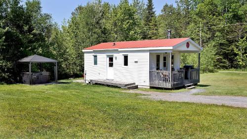 a small white shed with a red roof and a gazebo at Aux Pignons Rouges Camping & Chalets in Saint Romain