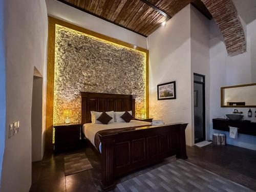 a bedroom with a bed and a large stone wall at HOTEL BOUTIQUE CASONA 65 in Puebla