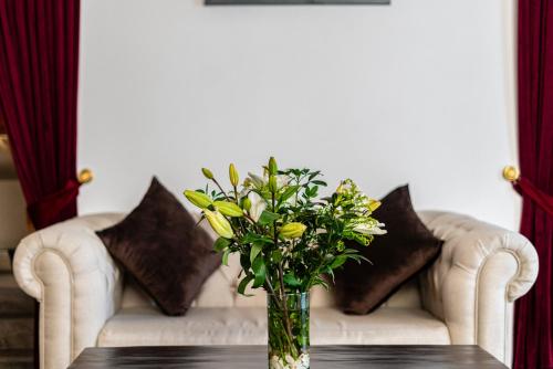 a vase of flowers on a table in front of a couch at HOTEL BOUTIQUE CASONA 65 in Puebla