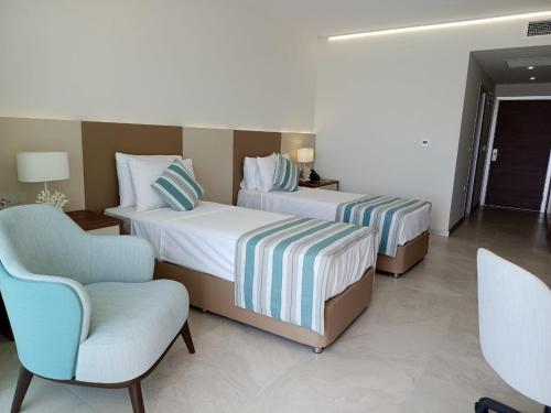 una habitación de hotel con 2 camas y una silla en Gadileh Resort Hotel, en Yibuti