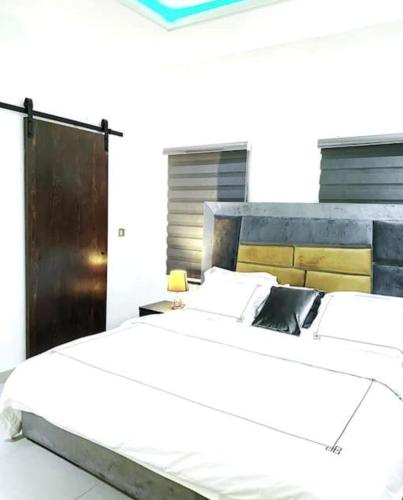 a bedroom with a large white bed with a headboard at Luxurious 2 bedroom Apartment with Private Chef in Lagos