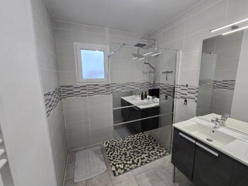 a white bathroom with a shower and a sink at Maison de la forêt in Dole