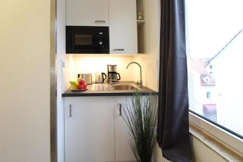 a small kitchen with a sink and a microwave at Downtown Apartments Ulm - im Herzen von Ulm & komfortable Boxspringbetten in Ulm