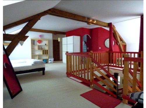 - une chambre avec un escalier et un mur rouge dans l'établissement Gite Loft 3 étoiles, à Tresnay