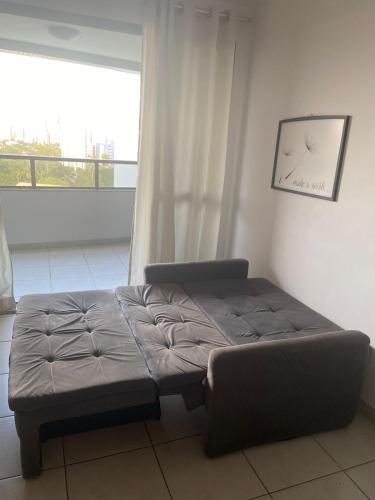 a bed sitting in a room with a window at Apartamento quarto/sala, Garibaldi Prime in Salvador