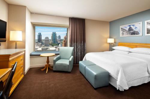 a hotel room with a bed and a desk and a window at Sheraton Grand Sacramento in Sacramento