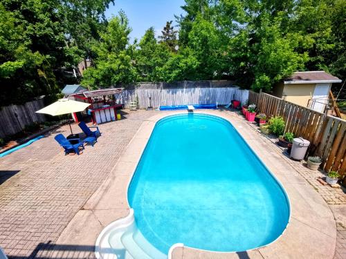 uma grande piscina num quintal com um guarda-sol e cadeiras em New Renovated Cozy Bedroom with Private washroom em Toronto
