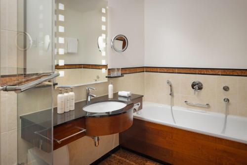 a bathroom with a sink and a tub at Arabella Jagdhof Resort am Fuschlsee, a Tribute Portfolio Hotel in Hof bei Salzburg