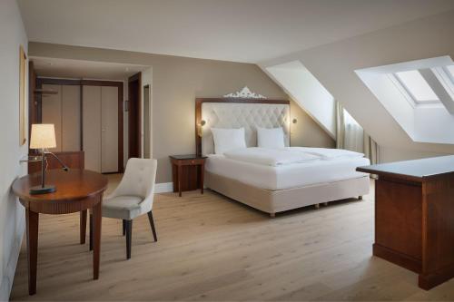 a bedroom with a bed and a table and a desk at Arabella Jagdhof Resort am Fuschlsee, a Tribute Portfolio Hotel in Hof bei Salzburg
