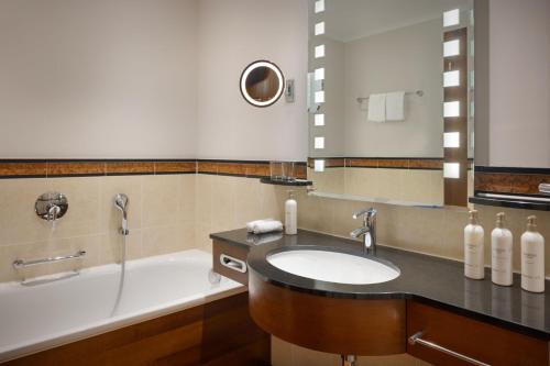 a bathroom with a sink and a bath tub at Arabella Jagdhof Resort am Fuschlsee, a Tribute Portfolio Hotel in Hof bei Salzburg