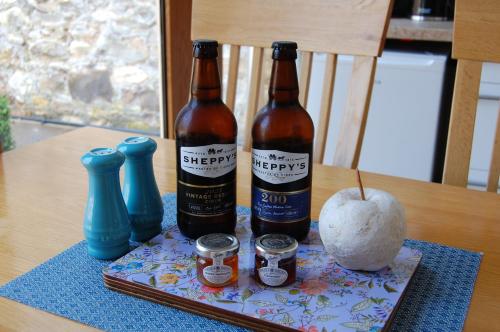 dos botellas de cerveza y una manzana en una mesa en The Stable - rural retreat, perfect for couples, en Taunton
